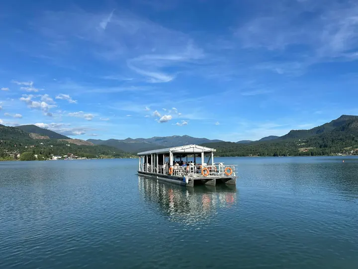 Ambarcațiune cu pasageri pe lacul Colibița, cu munții în fundal